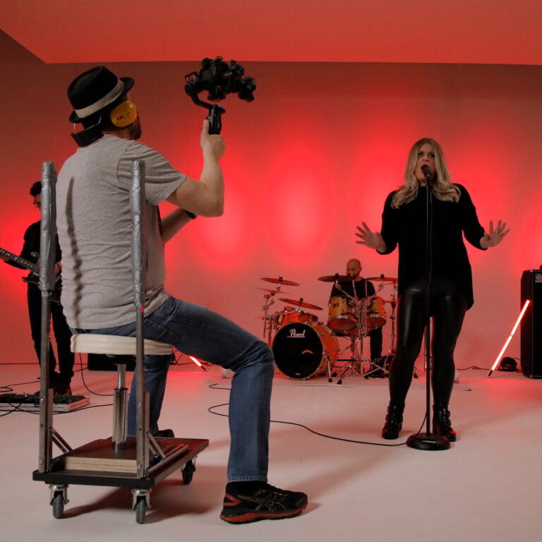 Making-of beim Musikvideo-Dreh der Band Radiant – Gitarrist vor Drums im roten Bühnenlicht mit Nebelmaschine