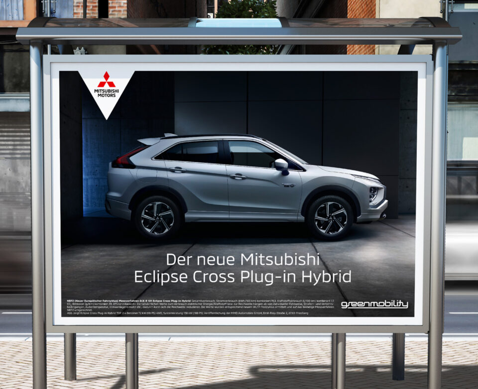 Werbeplakat an einer Bushaltestelle mit dem neuen Mitsubishi Eclipse Cross Plug-in Hybrid in Seitenansicht und dem Slogan „Der neue Mitsubishi Eclipse Cross Plug-in Hybrid“